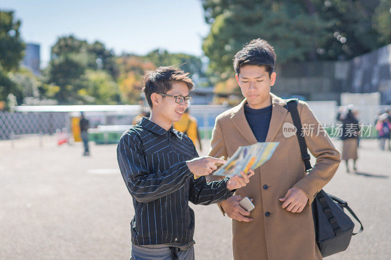 年轻的亚洲男子和日本朋友寻找旅游地点使用手机和花时间在亚洲旅行