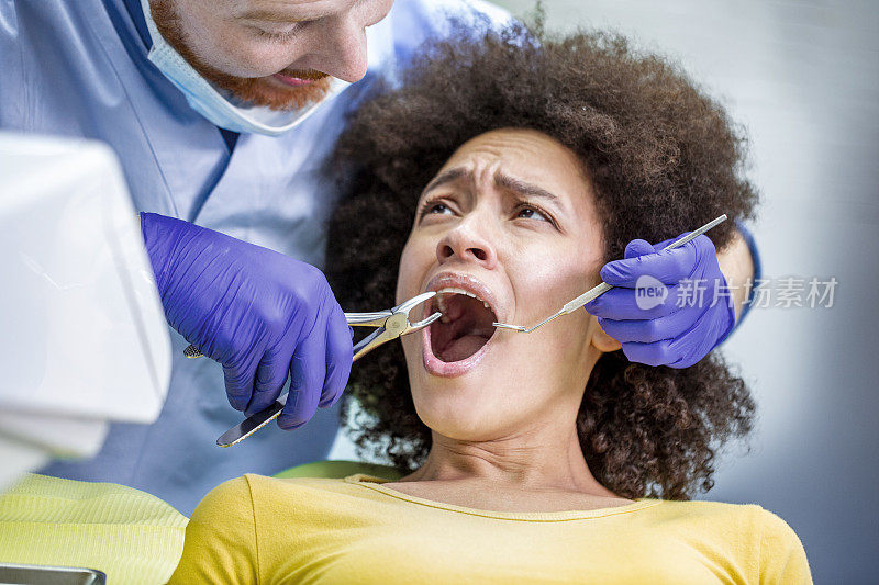 牙医用镊子从受惊的病人身上拔牙