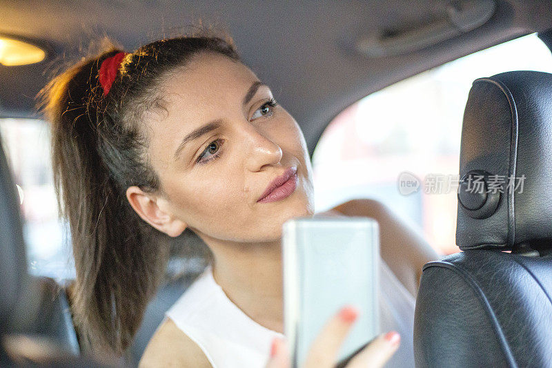 出租车里的年轻女子。女孩在用智能手机