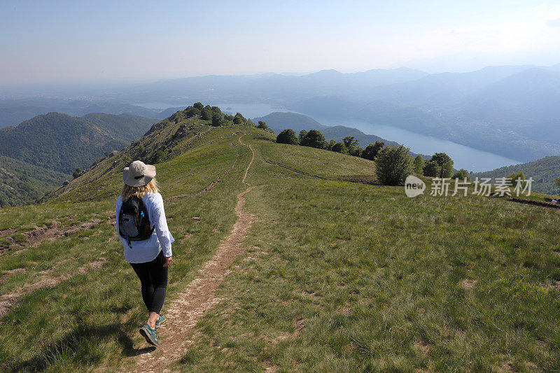 成熟的女人在湖上的山脊上徒步