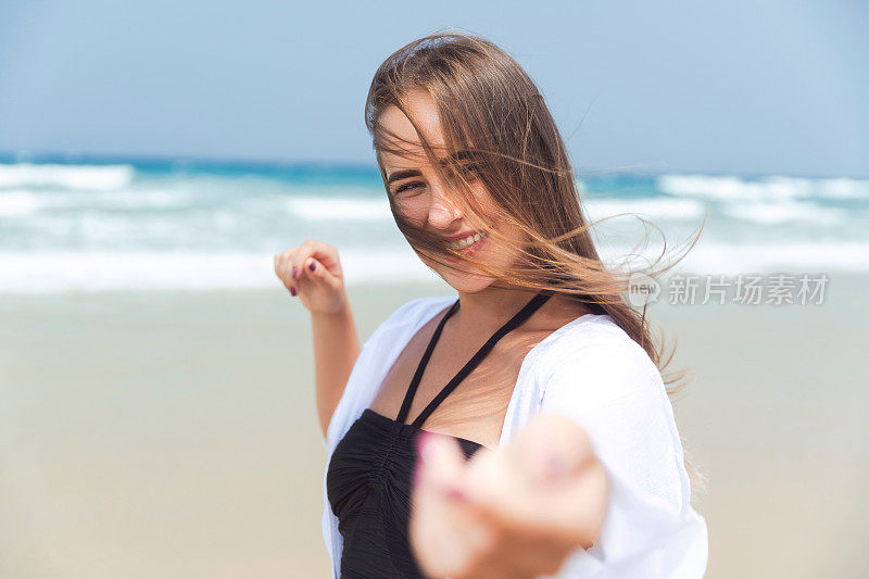 女孩在海滩上呼吸着新鲜空气，举起手臂对着镜头