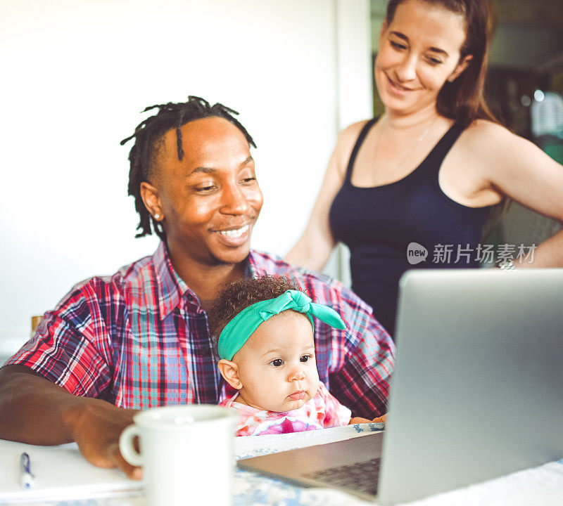非裔美国人的爸爸和他的女儿在电脑上工作，妈妈和家人一起使用电脑