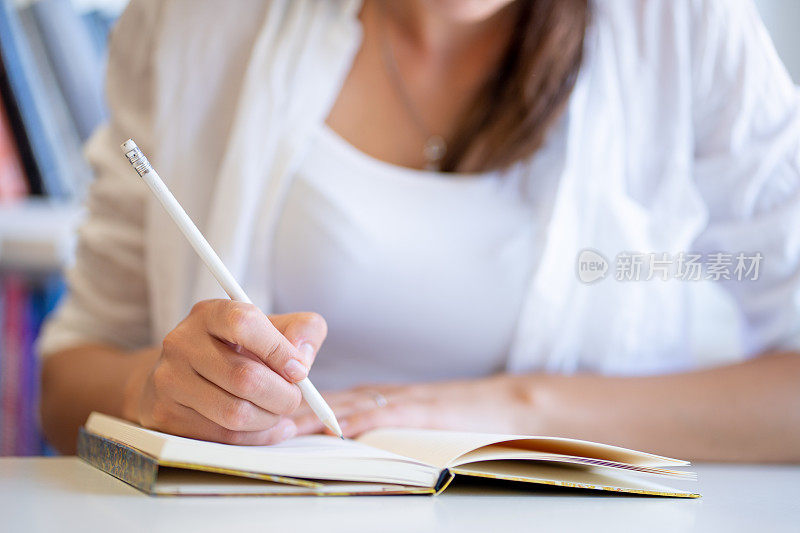 成年女性用铅笔在笔记本上写字