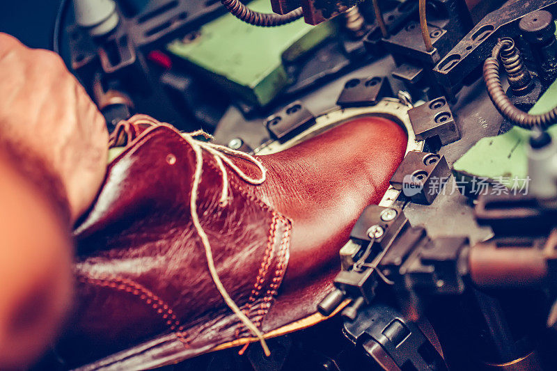 在手工制鞋行业中，经验丰富的鞋匠使用专用机器将鞋子放到模具上