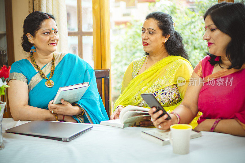 三个女人在家里一起讨论和做她们的网上生意。