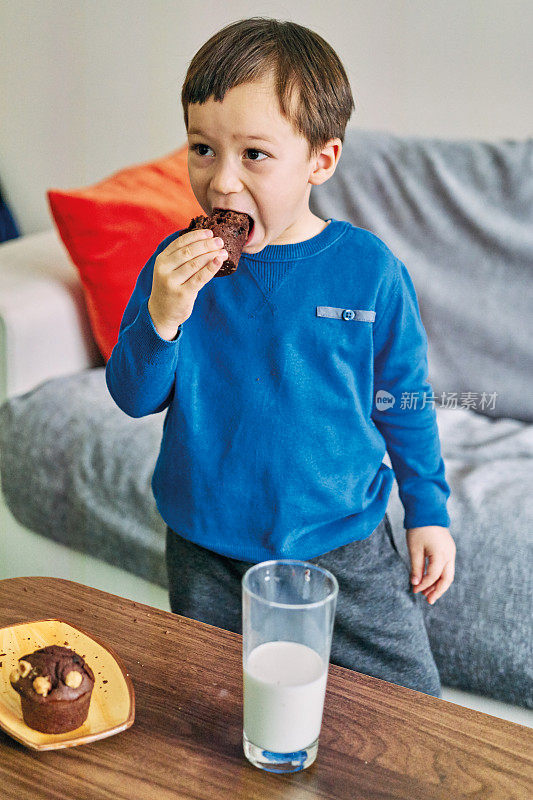 2-3岁可爱的孩子喝牛奶吃蛋糕。他喜欢牛奶。