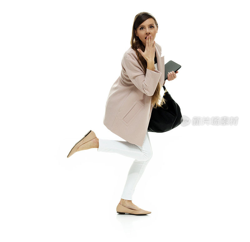 白种人年轻女性在白色背景下锻炼，穿着夹克，拿着钱包，使用数码平板电脑