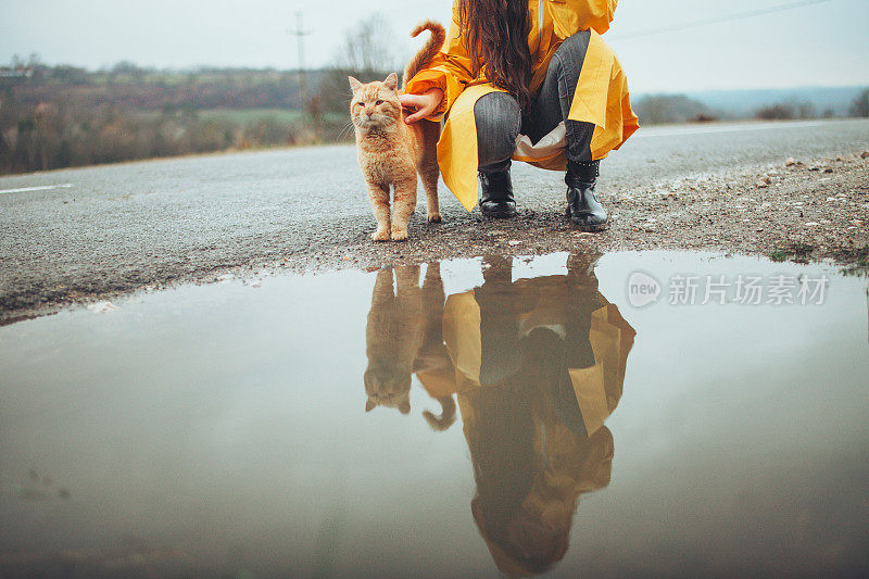 快乐的女孩和猫在大自然的雨