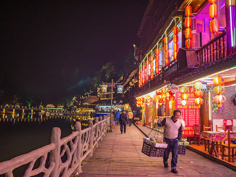 凤凰古城傍晚的人行道上，陌生的中国人在铺摊子。凤凰古城或凤凰县是中国湖南省的一个县