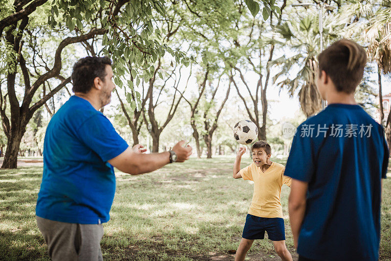爸爸和儿子们在公园里踢足球