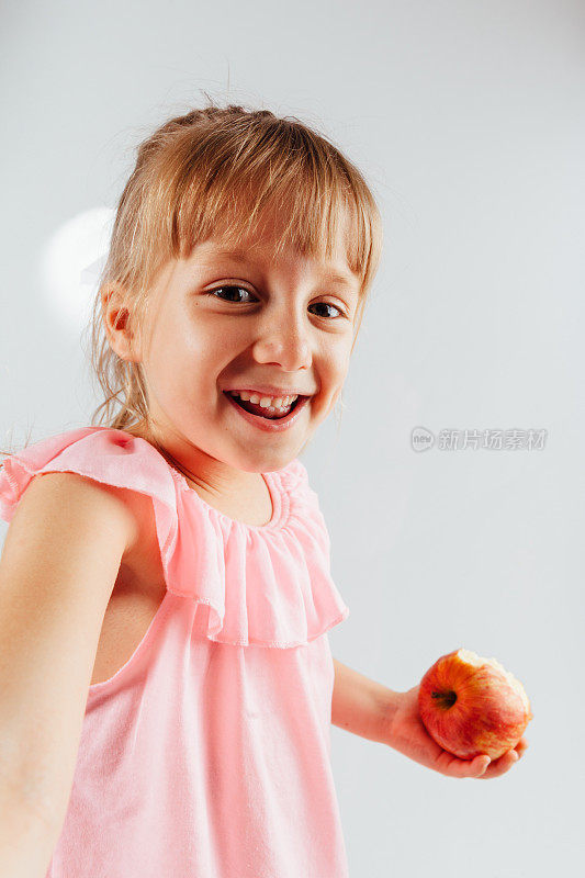 一个顽皮的小女孩拿着苹果的肖像