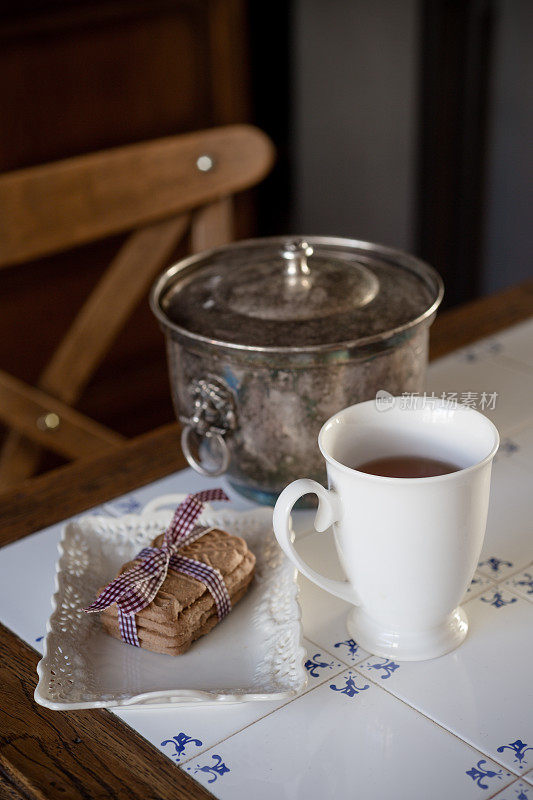 一杯茶，茶壶和饼干在桌子上-库存照片