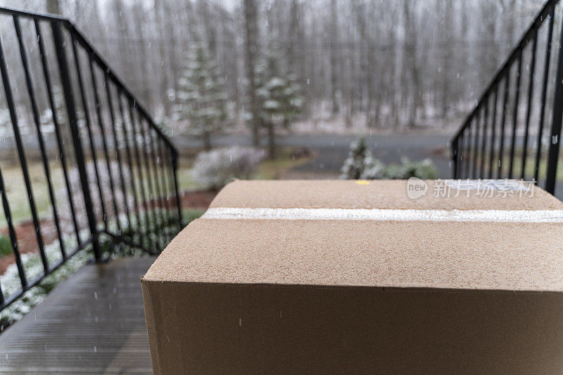 装着订好的货物的纸板箱被送到门口，下着雨放在门口的门廊上。
