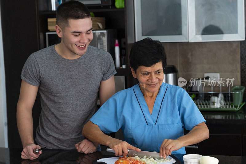 年轻男子接受烹饪课程从她的家庭助手从她的家庭厨房