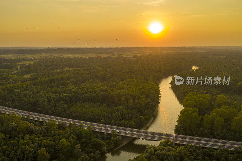 鸟瞰图的河流和道路通过森林在阴沉的日出