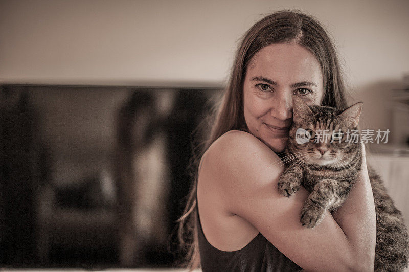 只是爱-美丽的女人与她的可爱的猫在客厅摆姿势