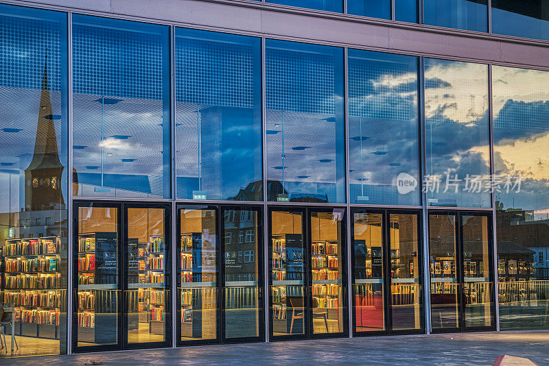 日落时分，Dokk1图书馆的玻璃入口反射出了奥尔胡斯的天际线，形成了浓厚的晚霞天空和云彩