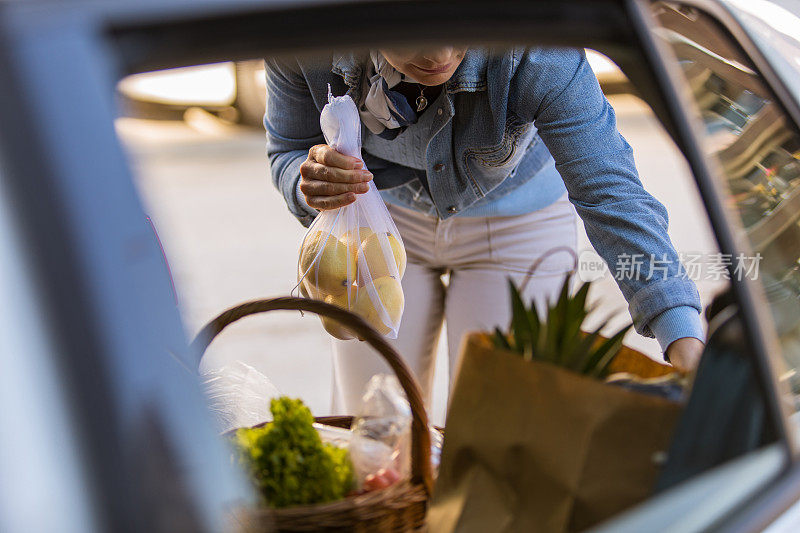 一个女人正把从农贸市场买的东西装进后备箱