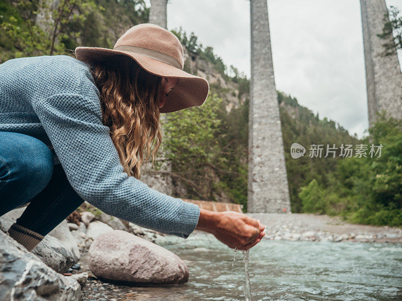 从小河里舀水的妇女