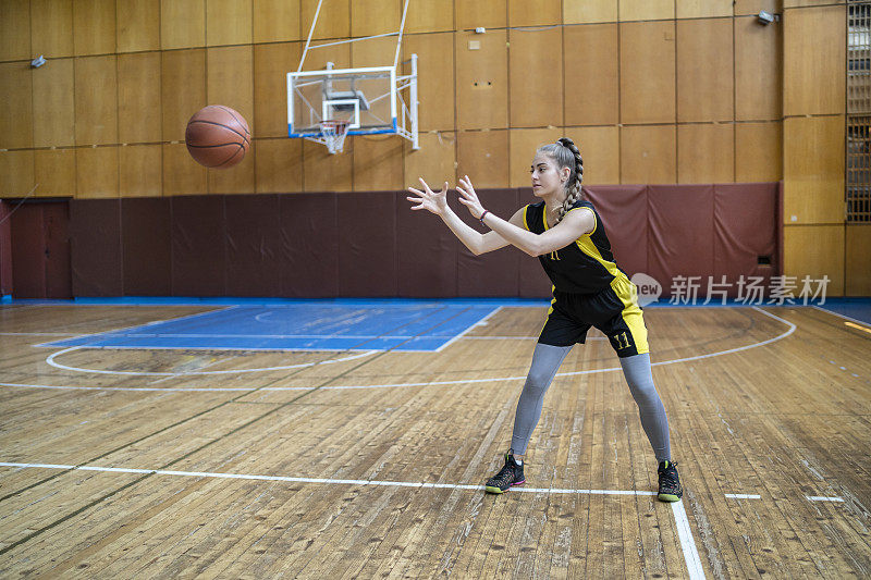 少女在学校礼堂练习篮球