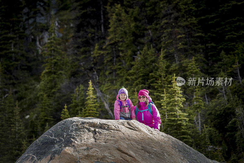 在阴沉的天气里，单亲妈妈带着女儿在惠斯勒高山徒步旅行。