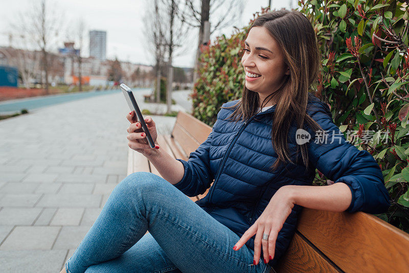 一个快乐的年轻女子坐在长椅上，正在进行视频通话