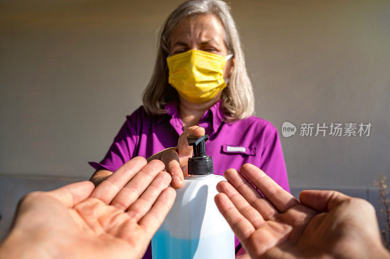 画着戴着口罩的老妇人在张开的手掌上喷洒消毒剂