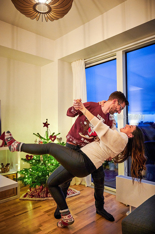 这是一对深情的年轻夫妇在圣诞节期间在家里一起跳舞的照片