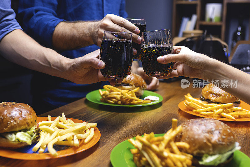 人们在吃汉堡包时碰可乐杯