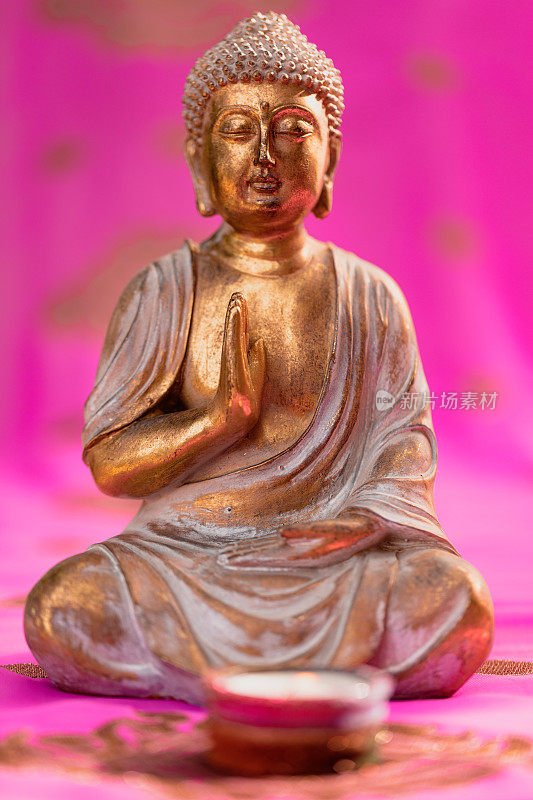 金佛与蜡烛坐在一个彩色的粉红色和金色印度教纱丽绳