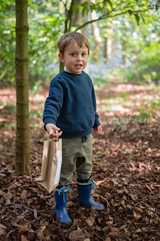 小男孩拿着活动包站在森林里