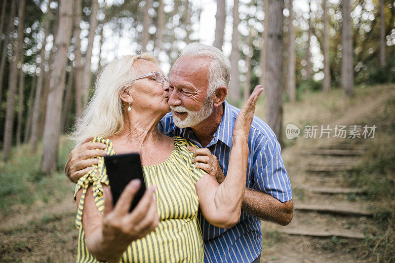 微笑老年夫妇在森林中使用手机