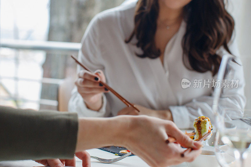 用筷子夹着寿司卷，在餐厅用餐