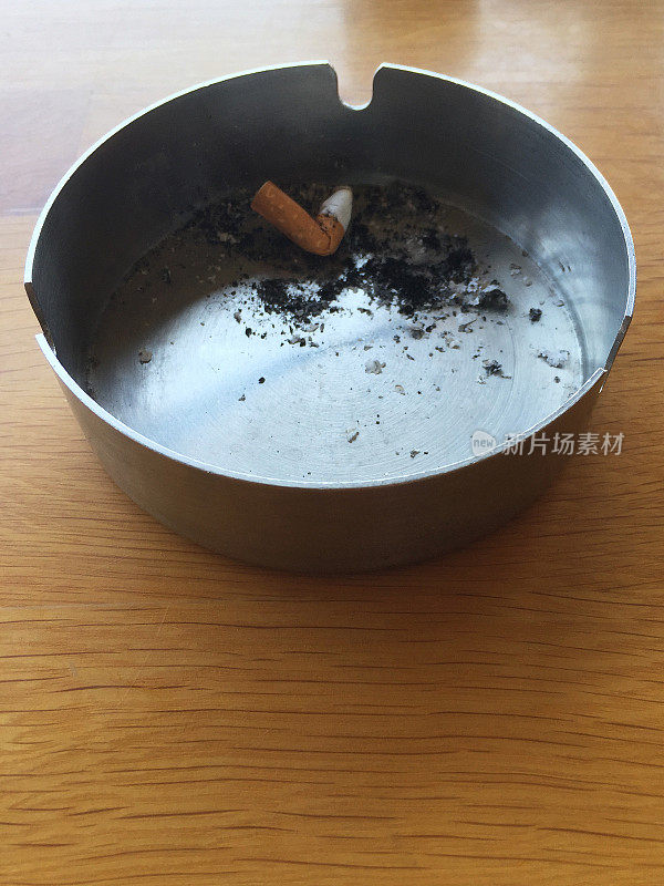 烟头在木桌上的烟灰缸里