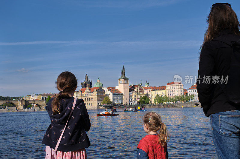 布拉格度假体验——年轻的一家人俯瞰着伏尔塔瓦河走向老城。