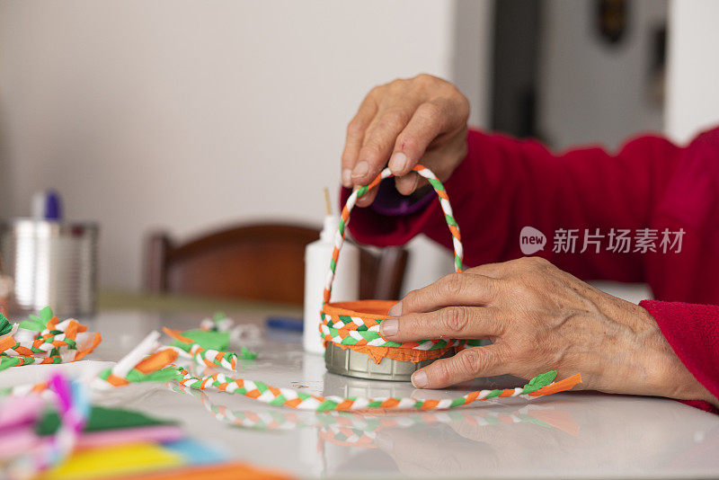 一位老妇人的手正在用材料制作工艺品