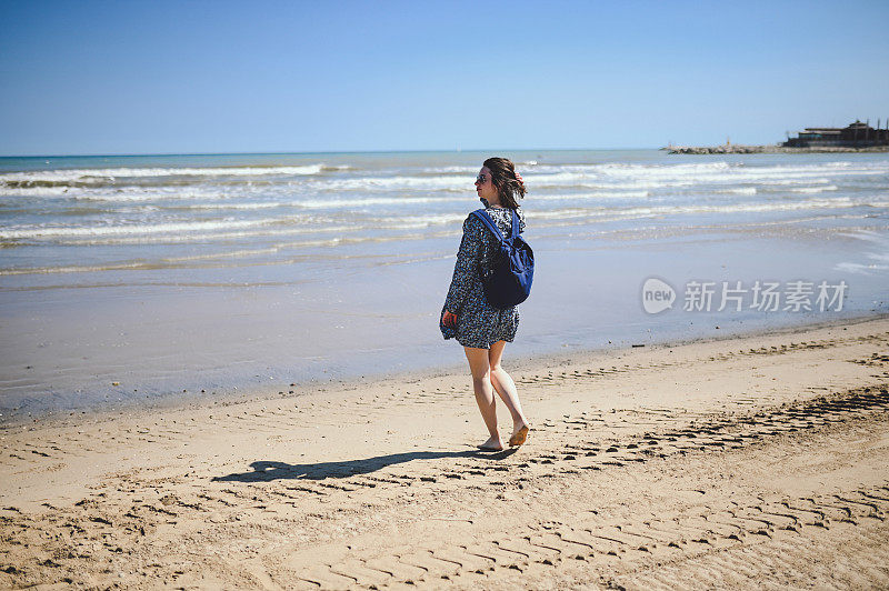 中年徒步旅行者沿着沙滩走向大海，欣赏风景。