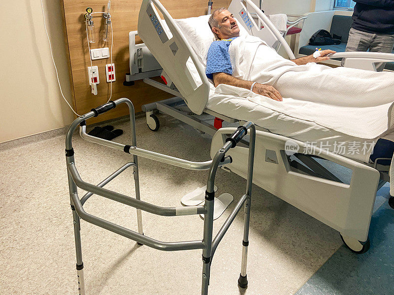 手术后躺在病床上的男病人和病房内的学步车