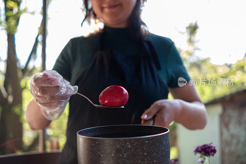 一位兴高采烈的年轻女子用勺子从红漆中取出一个红鸡蛋。