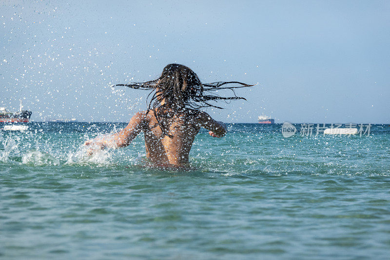 他用手在海里泼水。一个夏天的早晨。忒涅多斯岛。爱琴海北部，12岁的帅哥。长头发的