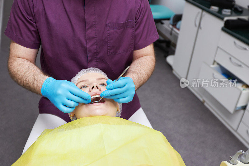 一名男性牙医卫生员检查龋齿和牙龈疾病的特写手