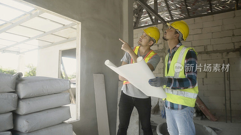 建筑工人和建筑师在施工现场审阅图纸，讨论工程方案。