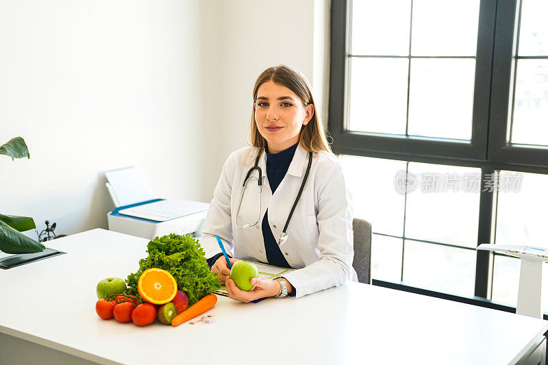 一位健康营养学家拿着一个苹果和蔬菜水果在她面前制定膳食计划