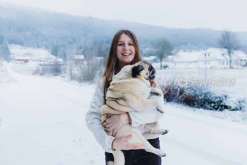一个快乐的女人在挪威乡下和她的狗一起思考冬天的时光