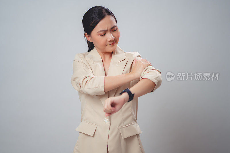 患有手臂疼痛的亚洲妇女孤立地站在白色背景上。
