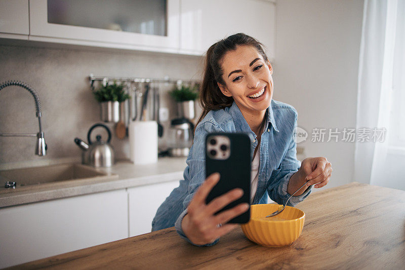 年轻女子一边用手机一边吃麦片配牛奶