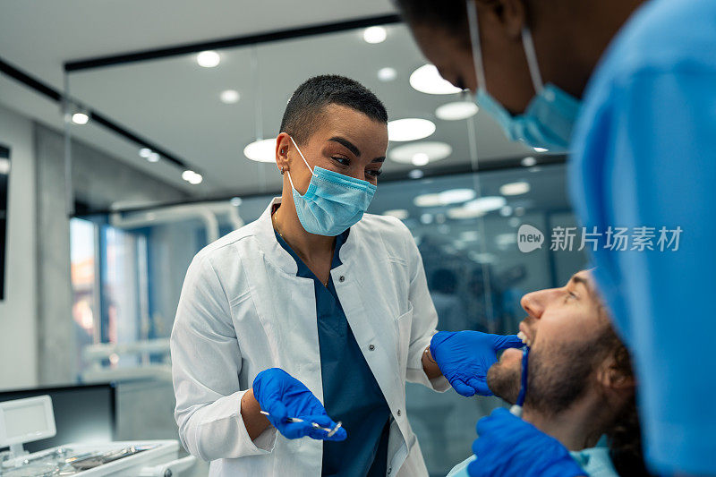 在牙科诊所接受牙齿检查时，戴口罩的女牙医与男病人交流