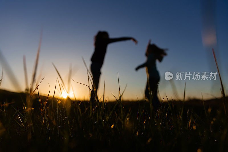 一对母女在田野里跳舞的剪影