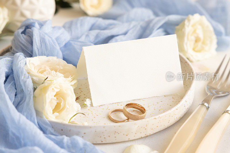 折叠卡片附近的浅蓝色薄纱织物和奶油花在盘子上接近，复制空间，婚礼模型