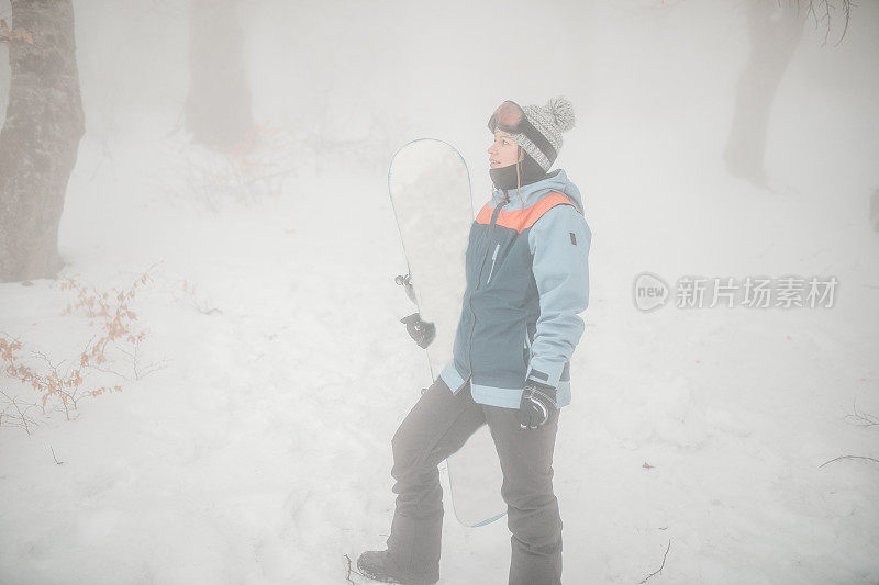 女子单板滑雪运动员准备骑一个滑雪板在山上在一个雾天